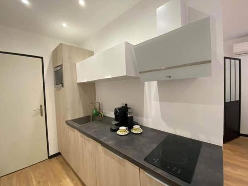 une cuisine avec des armoires blanches et un comptoir noir dans l'établissement Charming Apartment in Nice, à Nice
