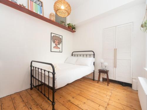 um quarto com uma cama e piso em madeira em Pass the Keys Rustic and Quirky Flat in Charming Charlton Village em Londres