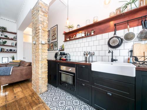 uma cozinha com armários pretos e um lavatório em Pass the Keys Rustic and Quirky Flat in Charming Charlton Village em Londres