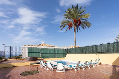 une terrasse avec une table, des chaises et un palmier dans l'établissement Villa esclusiva a 1 chilometro da Playa de Los Cristianos, à Los Cristianos