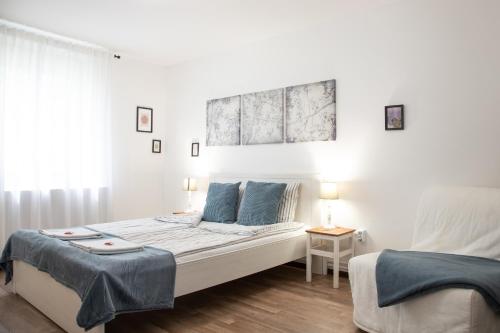 a white bedroom with two beds and two lamps at Csillagvirág Apartman Gyula in Gyula