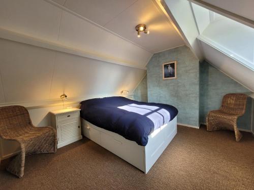 a bedroom with a large bed and two chairs at B&B Villa Giethoorn - canalview, privacy & parking in Giethoorn