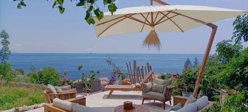 een patio met een parasol, stoelen en een tafel bij Villa Magnolia in Santa-Maria-di-Lota