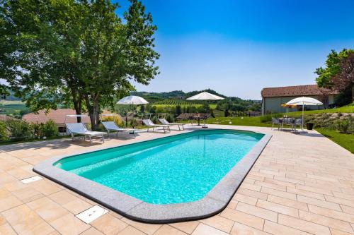 una piscina en un patio con sillas y sombrillas en TidHouse - Bed and Breakfast with private pool and free parking, en Motta