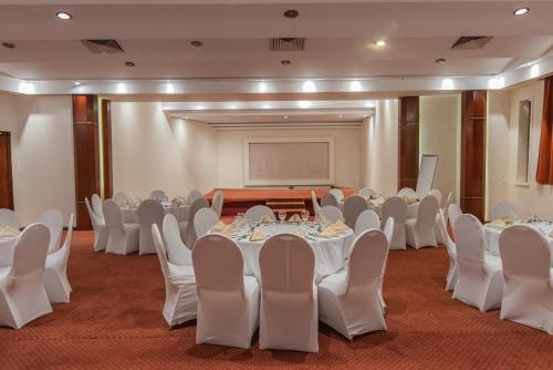 a banquet hall with white tables and chairs and a podium at Dexon Roma Hotel in Hurghada