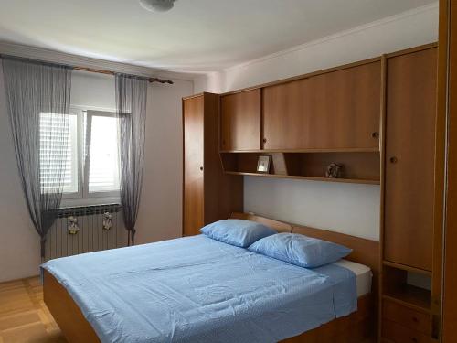 a bedroom with a bed with blue sheets and wooden cabinets at Guest Accommodation Grozdanić in Dubravice