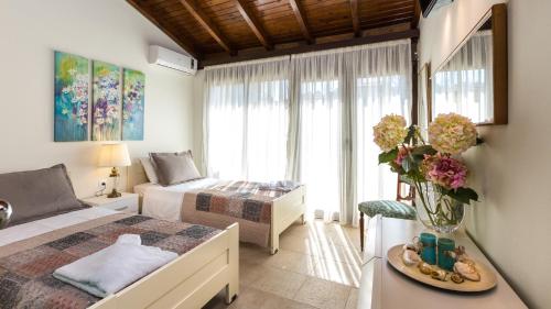 a bedroom with two beds and a table with a vase of flowers at Penelope Home in Panormos Rethymno