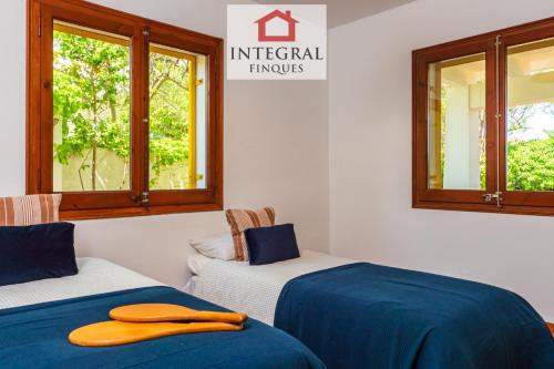 two beds with blue and white sheets and windows at La Masia de la Fosca in Palamós