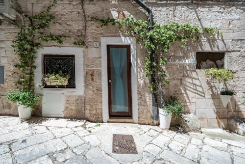 a stone building with a door and two potted plants at Vico di Ostuni Apartments by Rentbeat in Ostuni