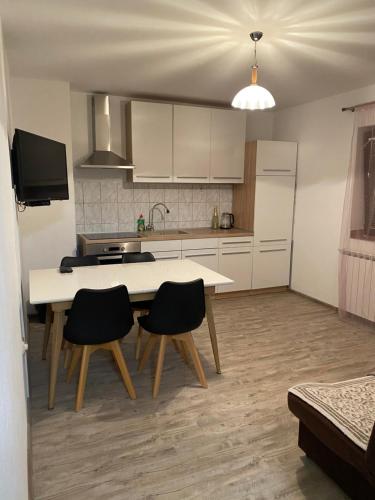 a kitchen with a table and chairs in a room at Apartman Laura in Smoljanac