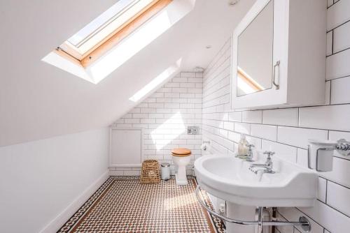 a white bathroom with a sink and a toilet at Sea House in Southwold