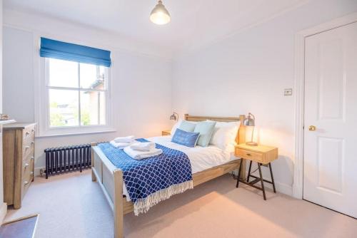 a bedroom with a bed with blue sheets and a window at Sea House in Southwold