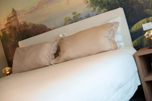a white bed with pillows and a painting on the wall at Relais La Dolce Vite in San Vendemiano