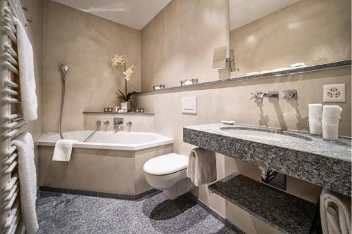 a bathroom with a tub and a toilet and a sink at Golf- & Sporthotel Hof Maran in Arosa