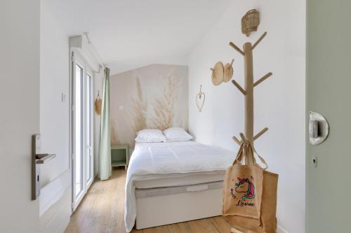 ein weißes Schlafzimmer mit einem Bett und einer Tasche auf dem Boden in der Unterkunft Calme et detente aux Sables d Olonne in Les Sables-dʼOlonne