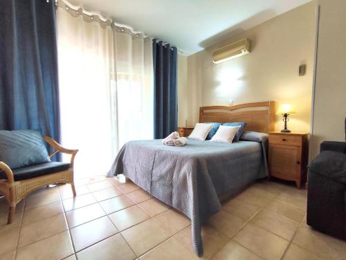 1 dormitorio con 1 cama con silla y ventana en Apartamentos BENALBEACH, en Benalmádena