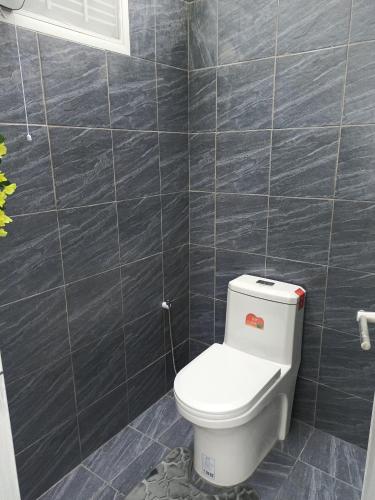 a bathroom with a toilet and a tiled wall at Everest Resort Samui - SHA Plus in Mae Nam