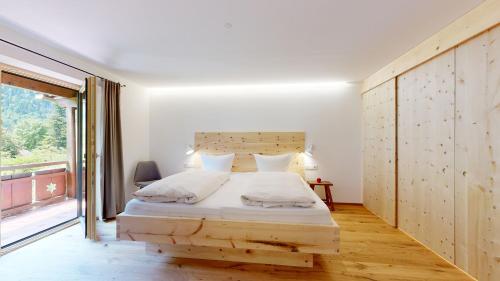 a bedroom with a bed and a large window at Fischer`s Postresidenzen Ettal in Ettal