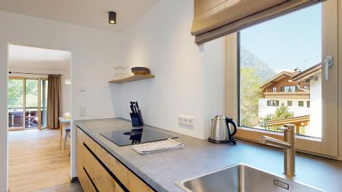 a kitchen with a sink and a large window at Fischer`s Postresidenzen Ettal in Ettal