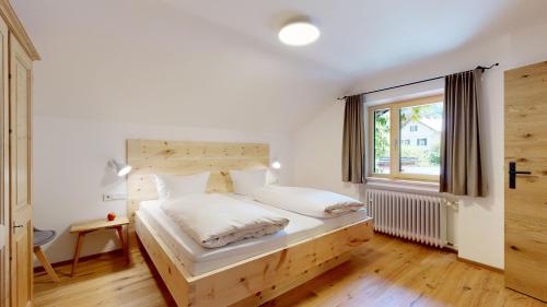 a bedroom with a bed with a wooden headboard and a window at Fischer`s Postresidenzen Ettal in Ettal