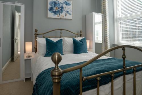 a bedroom with a bed with blue and white pillows at Spacious 4 Bed Victorian House with Sea Views in Ilfracombe