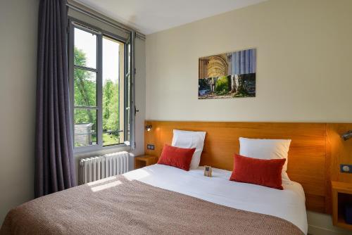 Schlafzimmer mit einem Bett mit roten Kissen und einem Fenster in der Unterkunft Moulin des Templiers Hôtel & SPA in Pontaubert