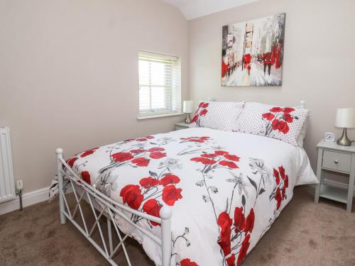 a bedroom with a bed with a red and white comforter at Olive Cottage in York