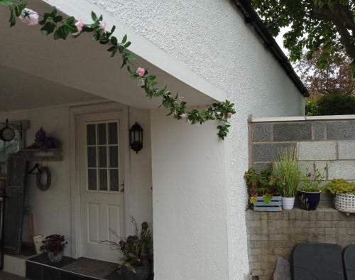 a white house with a door with flowers on it at Lovely Wee House in Lundin Links perfect beaches in Lundin Links