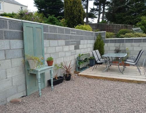 un patio con mesa y sillas junto a una pared de ladrillo en Lovely Wee House in Lundin Links perfect beaches, en Lundin Links