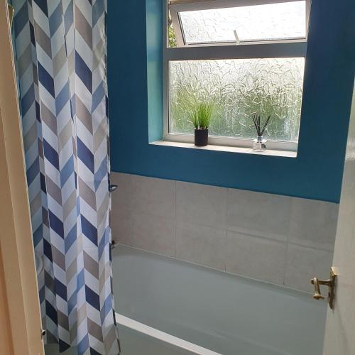 a bathroom with a shower curtain and a window at Alex's place in Hinckley