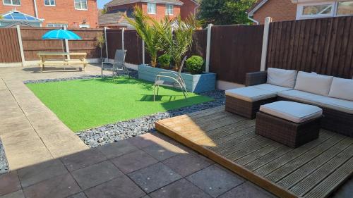 a patio with a couch and a table and grass at 3 bedroom detached by the sea in Prestatyn