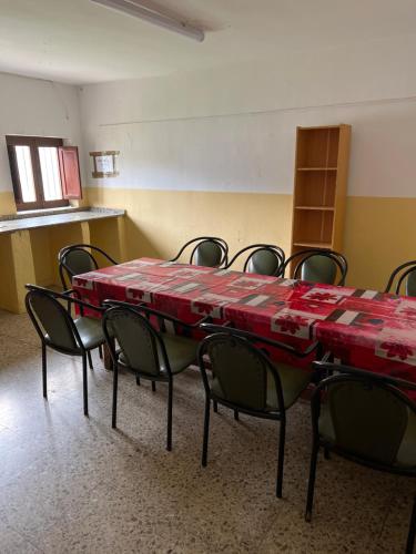 Albergue municipal في سان مارتين ديل كامينو: قاعة اجتماعات مع طاولة حمراء وكراسي