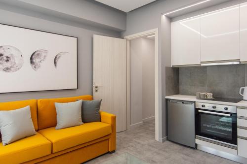 a living room with a yellow couch and a kitchen at Aire in Tripolis