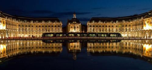 un gran edificio con un reflejo en el agua por la noche en Mon studio cosy à Pessac - Bordeaux, en Pessac