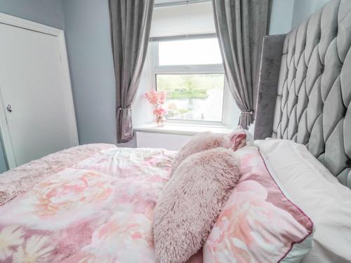 a bed with a floral blanket and a window at 4 Tyne View in Hexham