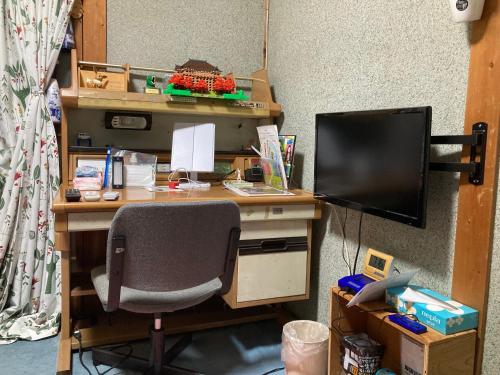 a computer desk with a monitor and a chair at Guest House Salt Beach in Yokkaichi