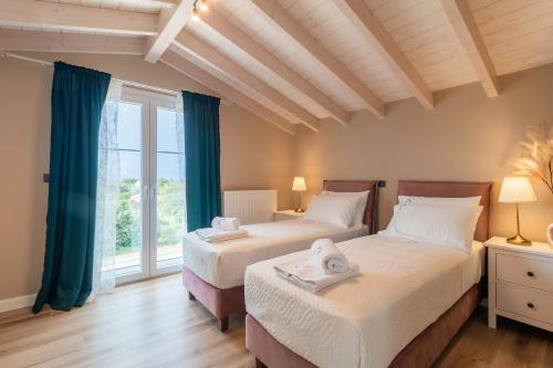 two beds in a room with a window at Melena Premium Suites in Roda