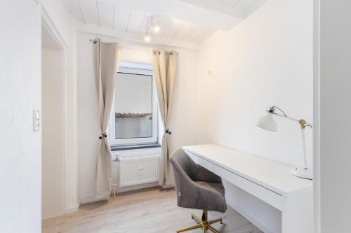 un bureau blanc avec une chaise à côté d'une fenêtre dans l'établissement Terrace apartment with 5 rooms, Whirlpool and BBQ, à Augsbourg