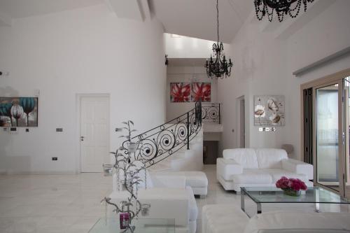 a living room with white furniture and a staircase at Eagles Cliff Villa in Kathikas