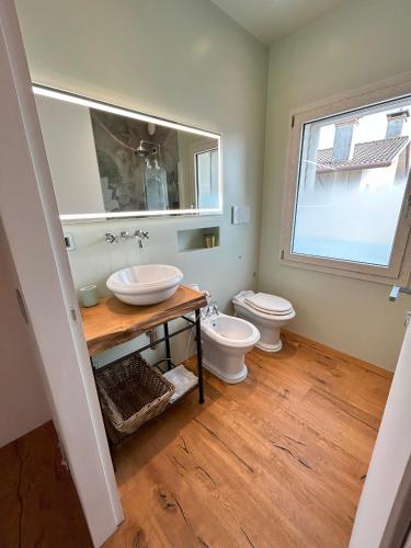 a bathroom with a toilet and a sink and a window at L'incanto Home 1 in Cittadella