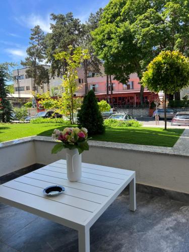a white table with a vase of flowers on it at Atmosphere by the Sea in Eforie Nord