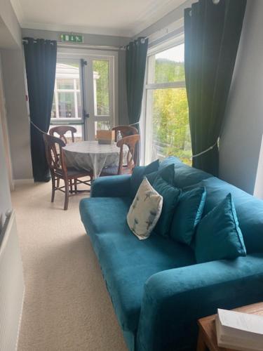a living room with a blue couch and a table at Sir Andrew Murray House in Strathyre