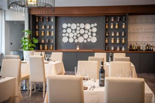 蒙卡列里的住宿－達斯娜最佳品質酒店，一间设有白色桌椅的餐厅,并提供葡萄酒瓶