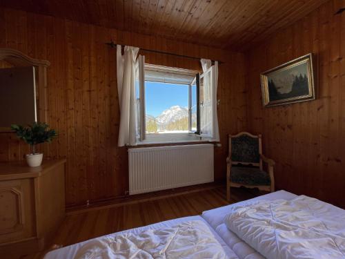 um quarto com uma cama, uma janela e uma cadeira em Forsthaus Reit im Winkl em Reit im Winkl