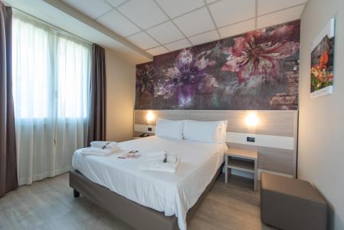 Best Quality Hotel La Darsena في مونكالييري: غرفة نوم بسرير كبير ولوحة على الحائط