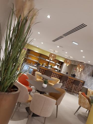 a restaurant with a table and chairs and a plant at Résidence Les Tisserands - Domitys in Beauvais
