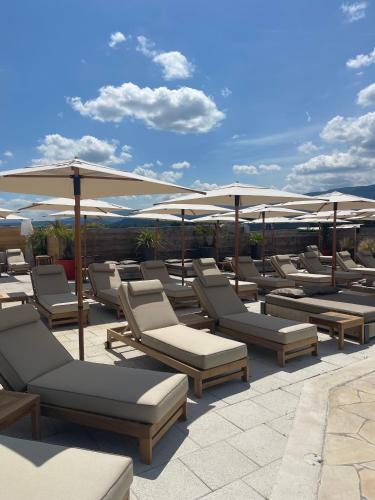 a row of lounge chairs and umbrellas on a patio at Les Loges du Luberon in Coustellet
