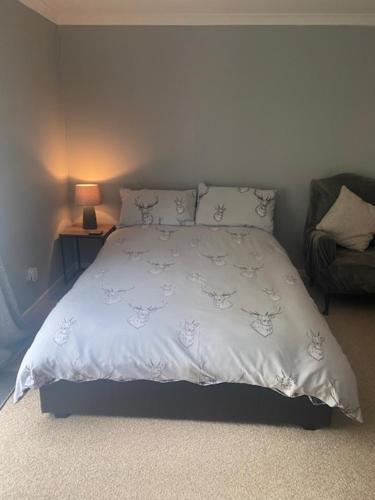 a bedroom with a bed with a white comforter and a lamp at Sir Andrew Murray House in Strathyre