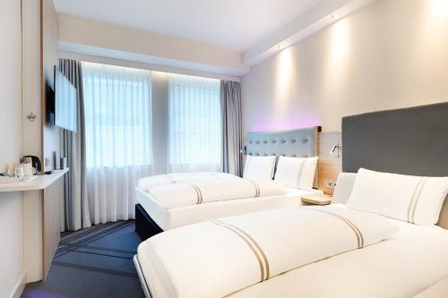 a hotel room with two beds and a television at Premier Inn Frankfurt Westend in Frankfurt/Main