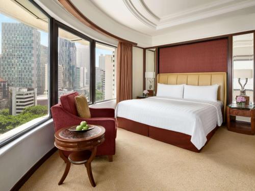 a hotel room with a bed and a chair and window at Shangri-La Kuala Lumpur in Kuala Lumpur